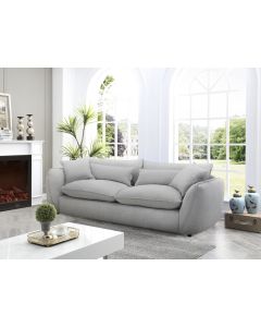 Muhkea 3,5-istuttava sohva harmaalla kangasverhoilulla. Muhkeat irtotyynyt sekä koristetyynyt.